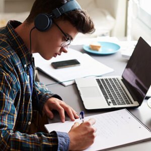Student studying with headphones and laptop representing focus, clarity, and balance in a fast-moving world