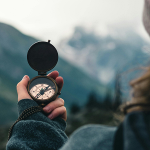 Person holding a compass in nature symbolizing clarity, purpose, and life direction