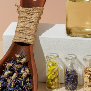 Wooden spoon with dried flowers and oils reflecting natural healing and plant-based wellness